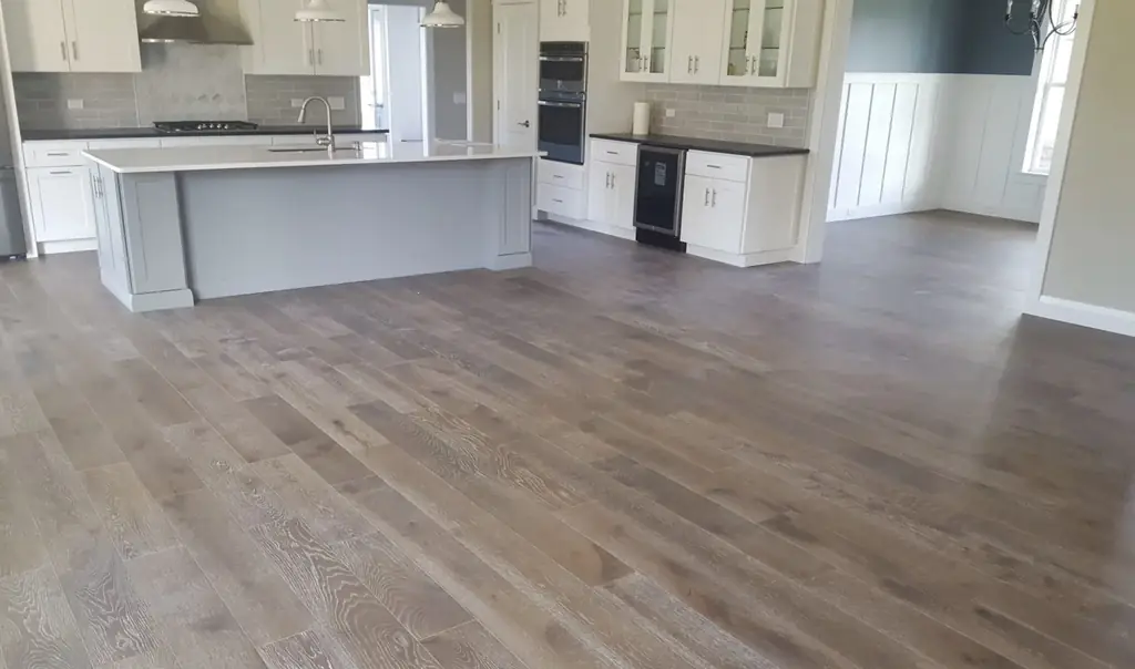 Open plan kitchen with wide plank hardwood flooring running through it