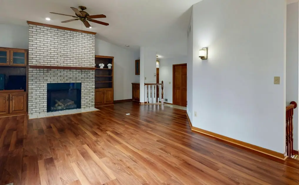 Living room with a brick fireplace and new laminate flooring